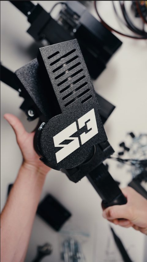 A SIMRIG SR3 actuator held in both hands at the assembly bench